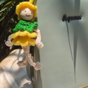 Handmade crochet doll bag charm with yellow dress attached to a handbag.
